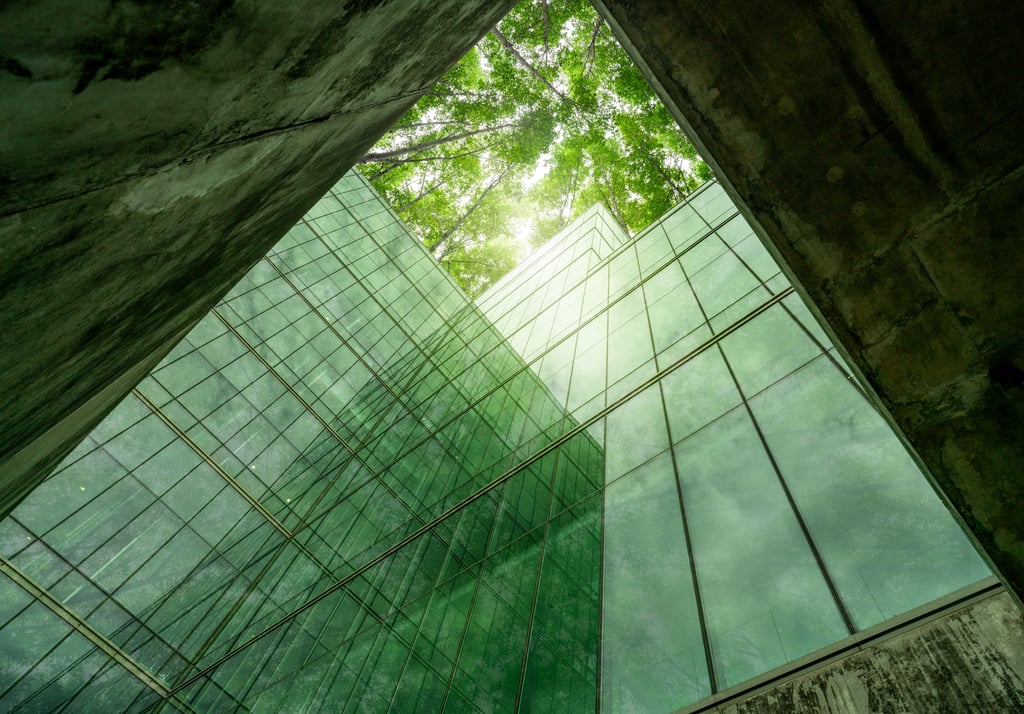 Edificio con fachada de vidrio rodeado de vegetación, representando la certificación RSB y el enfoque en biomateriales sostenibles y sostenibilidad verificable.