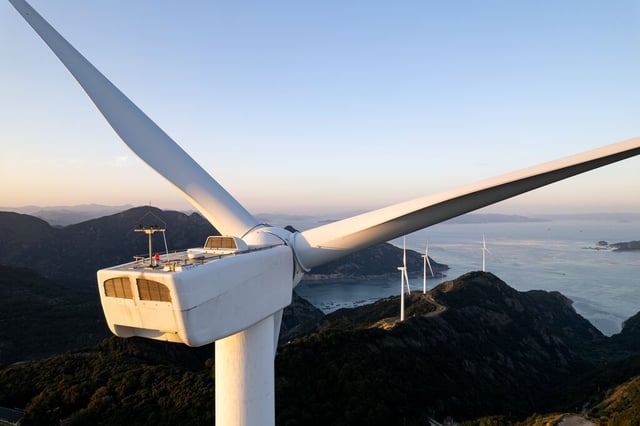 Wind turbines on coastal hills generating renewable energy, representing sustainable power and climate solutions