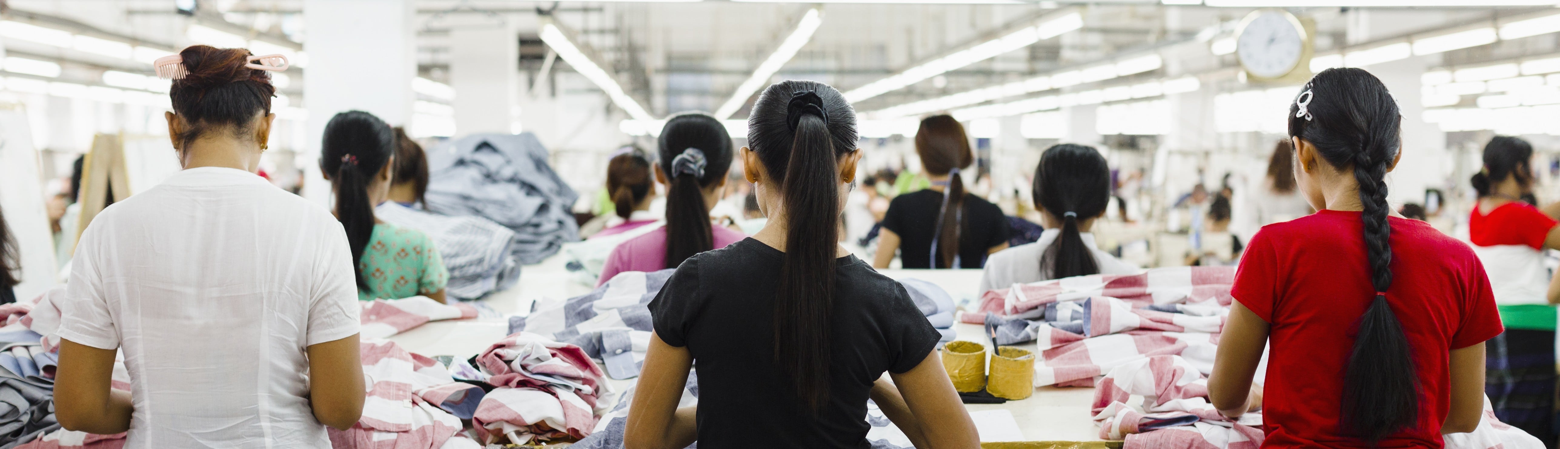 Trabalhadoras em linha de produção de confecção em ambiente fabril