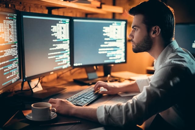 Especialista en ciberseguridad trabajando frente a varias pantallas, representando los servicios de pruebas de penetración y la evaluación de vulnerabilidades.