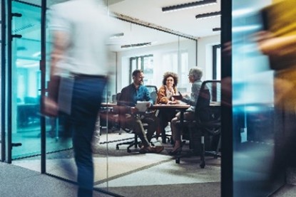 Business meeting in a modern glass-walled office with blurred pedestrian motion